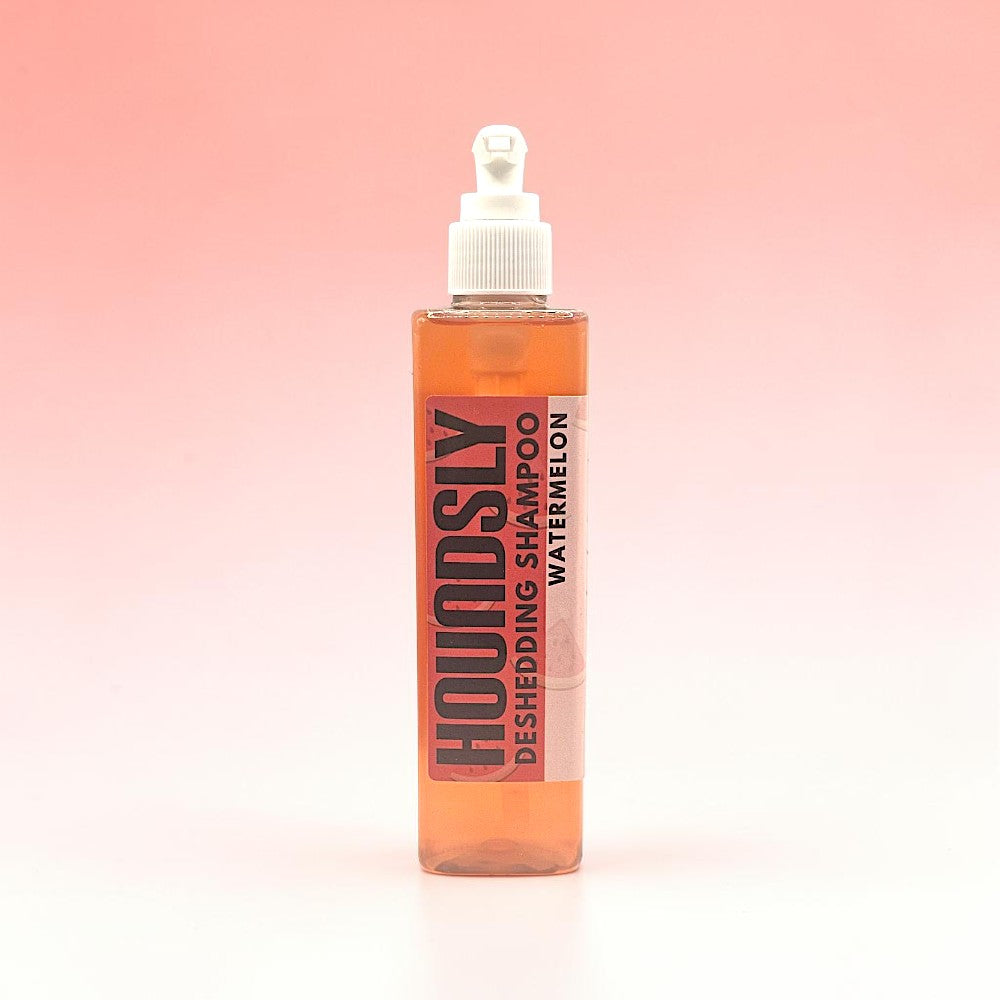 Houndsly Deshedding Dog Shampoo in Watermelon scent, a clear orange liquid in a pump bottle.