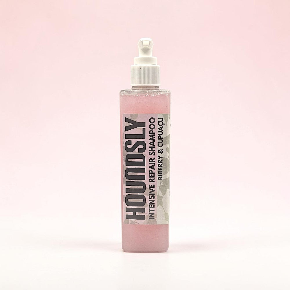 Houndsly Intensive Repair Dog Shampoo in Riberry & Cupuaçu, a pink liquid in a clear bottle with a pump dispenser.