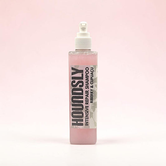 Houndsly Intensive Repair Dog Shampoo in Riberry & Cupuaçu, a pink liquid in a clear bottle with a pump dispenser.
